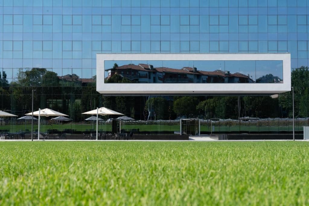 a picture of a building with umbrellas and grass at Life Hotel in Bergamo