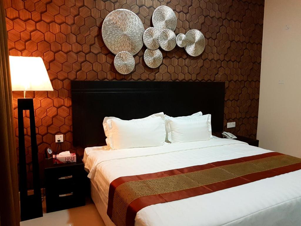 Tanuf Residency Hotel في نزوى‎: غرفة نوم مع سرير مع لوحات على الحائط