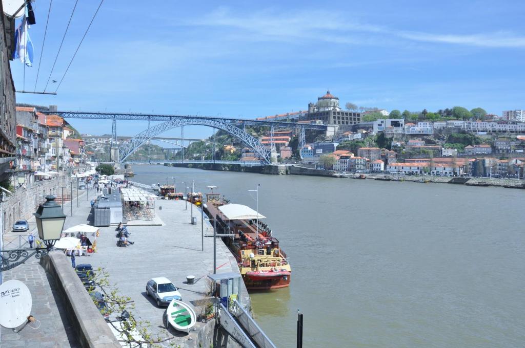 a boat is docked on a river with a bridge at RIBEIRA by YoursPorto in Porto