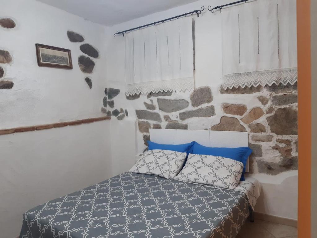 Tempesta Home في لاينوساي: غرفة نوم بسرير وجدار حجري