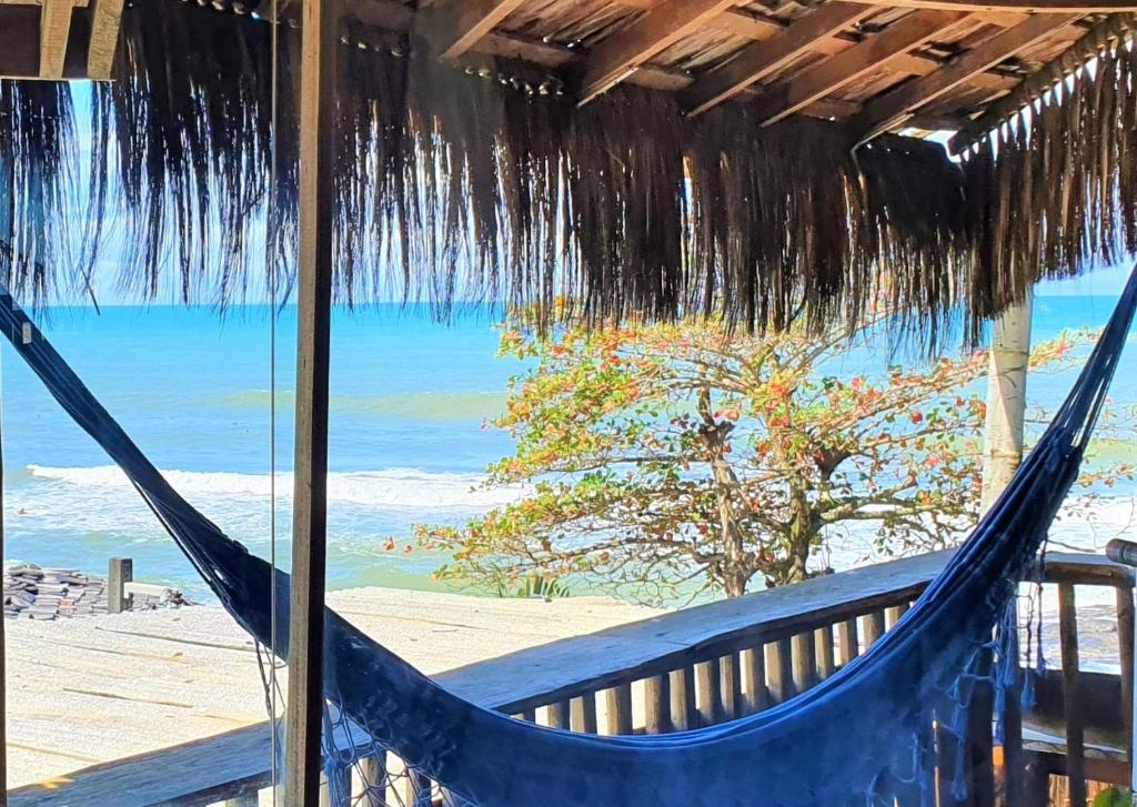 a hammock on a beach with a view of the ocean at Pousada Tãnara in Itacaré