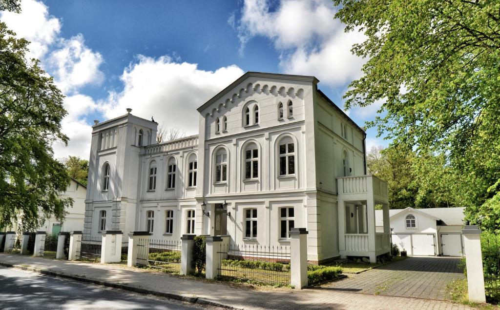 una casa blanca con una valla delante en Apartments Fürstenvilla Putbus, en Putbus