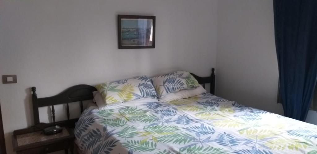 a bed in a bedroom with a blue and white comforter at Cottage near the mountains away from crowd in Las Palmas de Gran Canaria