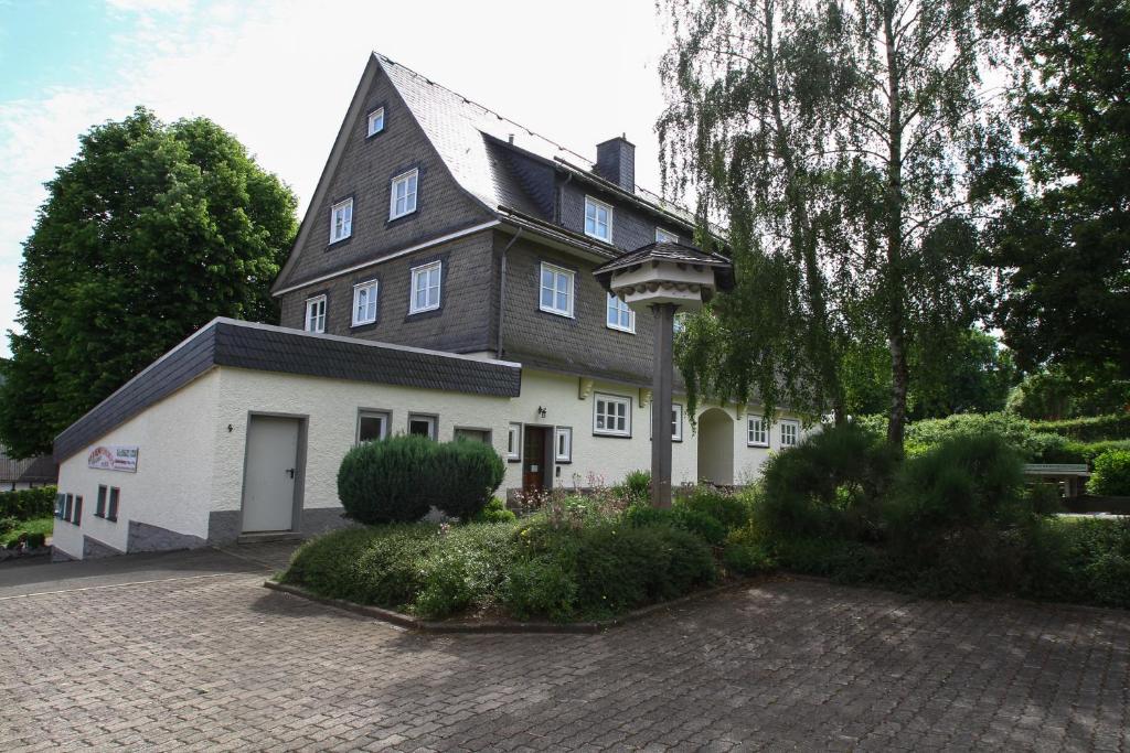 une grande maison blanche avec un toit noir dans l'établissement Fewo Alte Schule, à Willingen