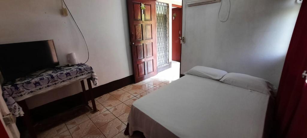Schlafzimmer mit einem Bett, einem Tisch und einem Fenster in der Unterkunft Tropical Dreams Hostel in Corn Island