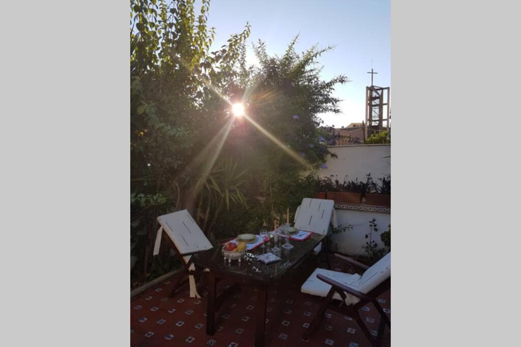 a table and chairs on a patio with the sun shining at Casa con jardín GRANADA, fácil aparcamiento calle in Granada