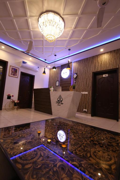 Un vestíbulo con un reloj en el suelo y una lámpara de araña. en Cuzzy Inn Hotel, en Lahore
