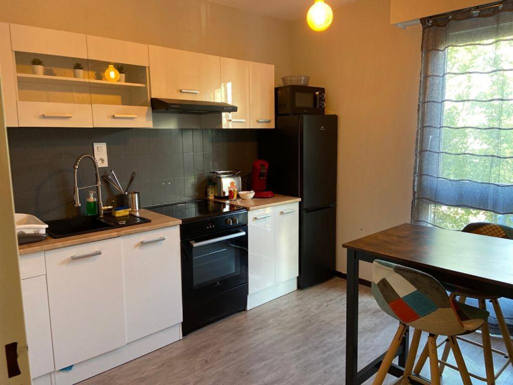 a kitchen with a black refrigerator and a table at STUDIO DIJON MARPAUX in Dijon