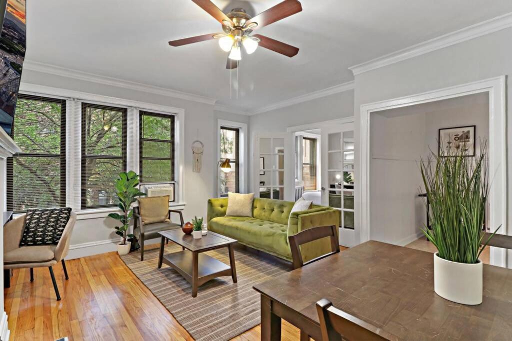 sala de estar con sofá verde y ventilador de techo en Vibrant & Well-Furnished 2BR Apartment - Roscoe 1A, en Chicago