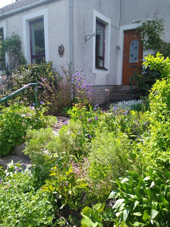 um jardim em frente a uma casa com flores em lovely 1 bedroom borders cottage em Town Yetholm