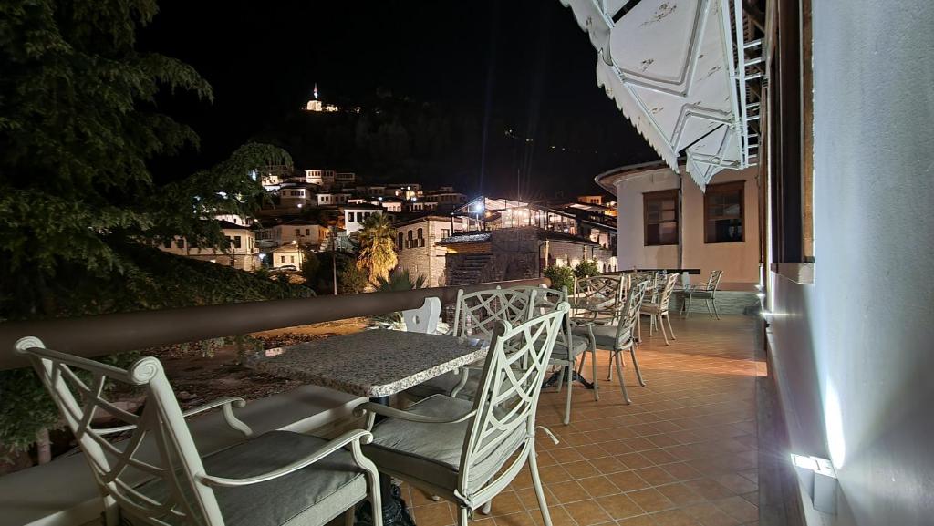 a row of tables and chairs on a balcony at night at Master Hotel in Berat