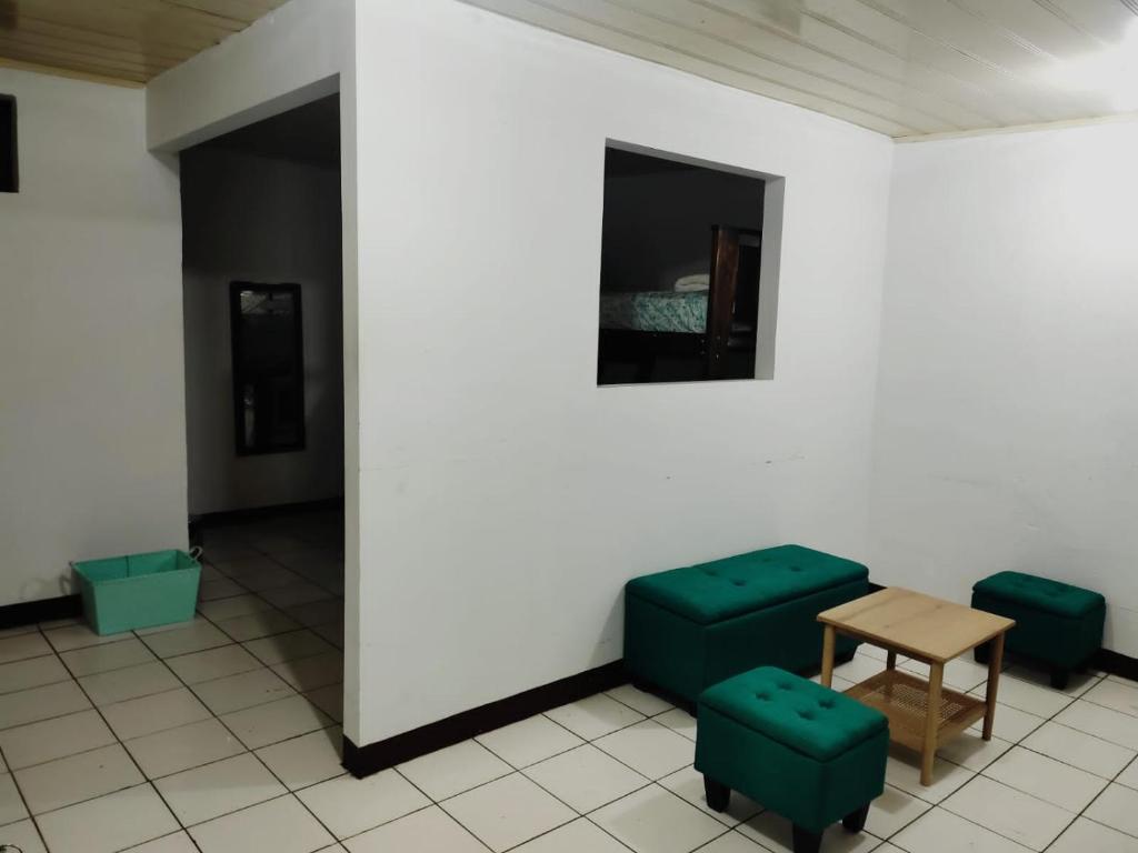 um quarto com duas cadeiras verdes e uma mesa em Departamentos Patricia em Alajuela
