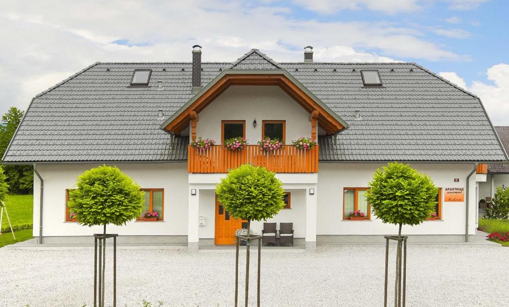 ein großes weißes Haus mit einem Balkon und zwei Bäumen in der Unterkunft Apartments Roberta in Bled