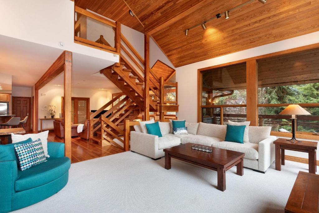 a living room with blue and white furniture and wooden ceilings at Luxury 5 Bedroom Blueberry Chalet in Whistler