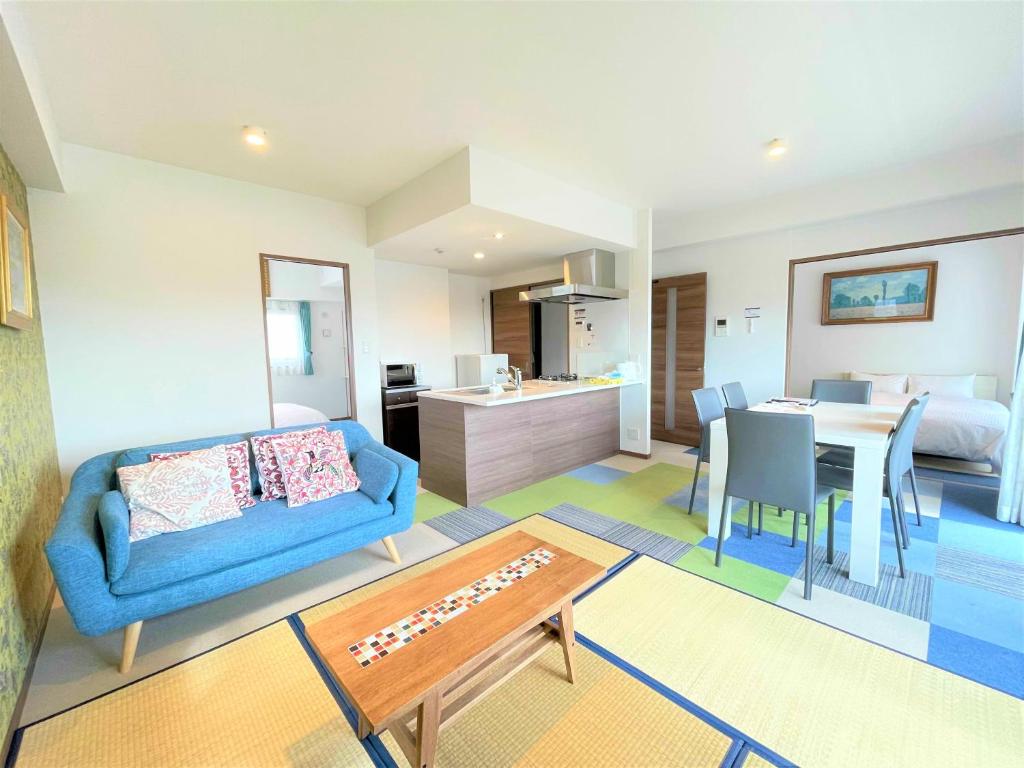 A.T. Hotel Hakata في فوكوكا: غرفة معيشة مع أريكة زرقاء وغرفة طعام