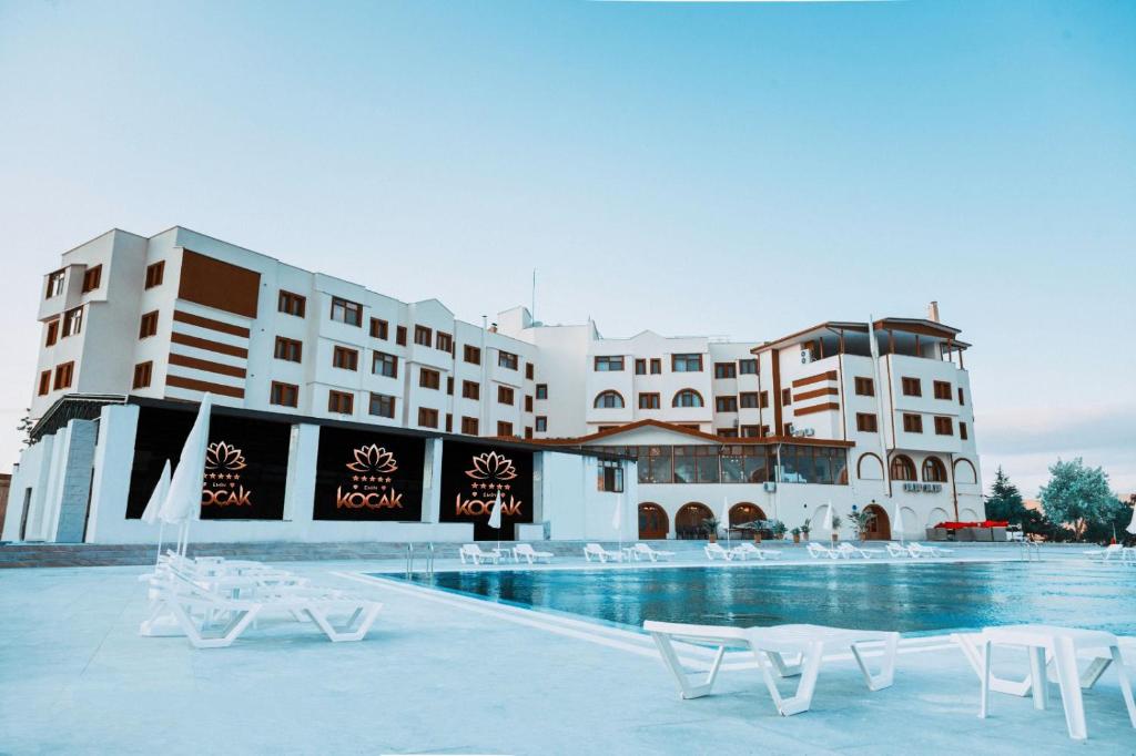 un hotel con piscina y sillas blancas en Emin Koçak Hotel Kapadokya, en Nevşehir