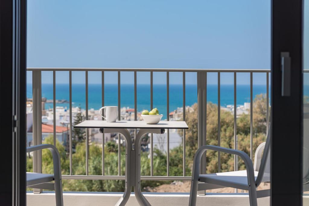 een tafel en stoelen op een balkon met uitzicht op de oceaan bij Kallithea Residence in Rethimnon