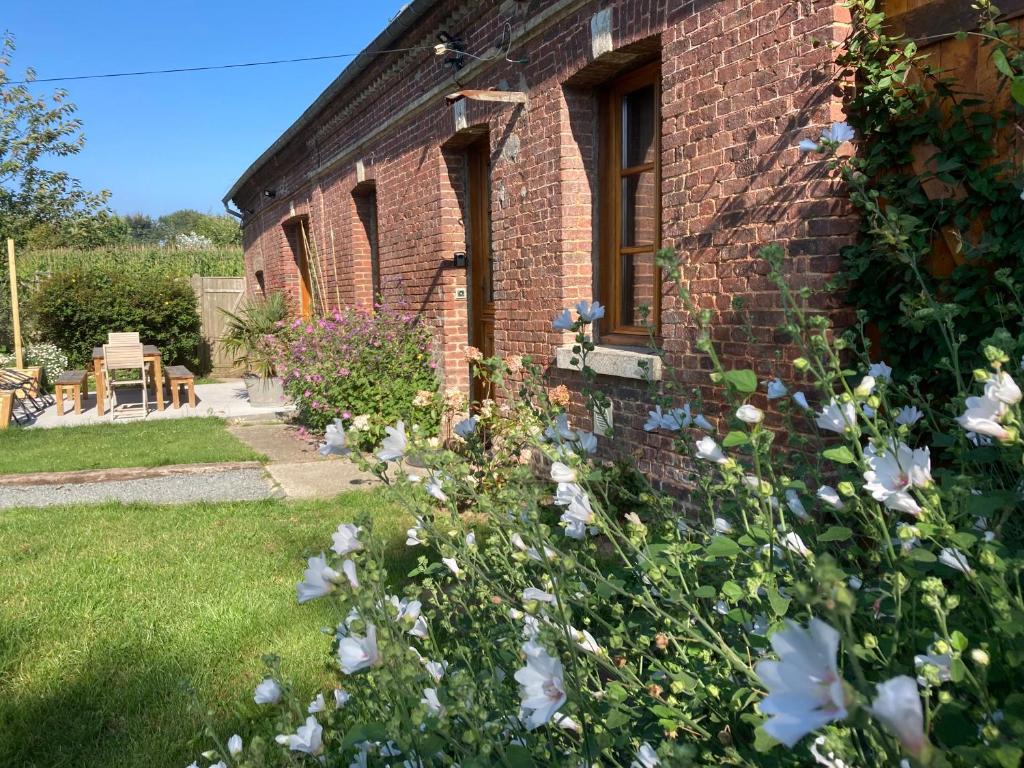 une maison en briques avec des fleurs dans la cour dans l'établissement Maison entre terre et mer proche Etretat, à Saint-Jouin-Bruneval