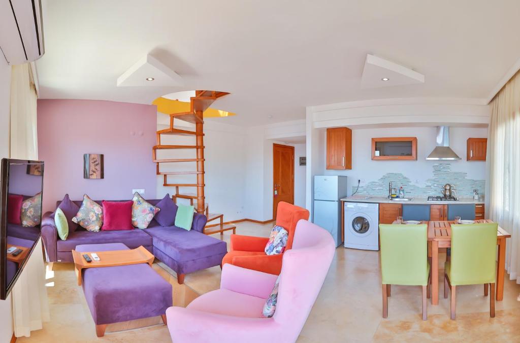 uma sala de estar com um sofá roxo e cadeiras coloridas em Çınarlar Apart Hotel KAŞ em Kas