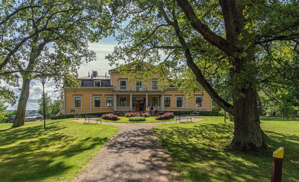 a large yellow house with a tree in front of it at Mukkulan kartano in Lahti