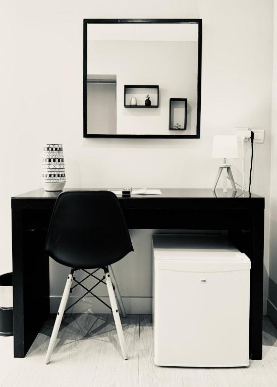a black desk with a black chair and a mirror at Hôtel Jules in Le Touquet-Paris-Plage