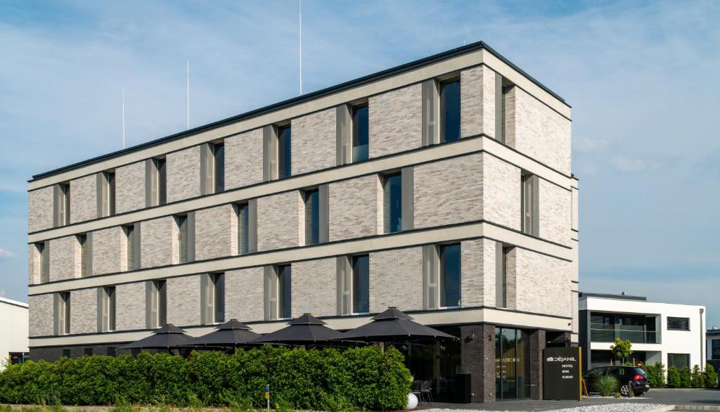 a large brick building with an umbrella in front of it at AKZENT Hotel DÉJANIL in Burgdorf