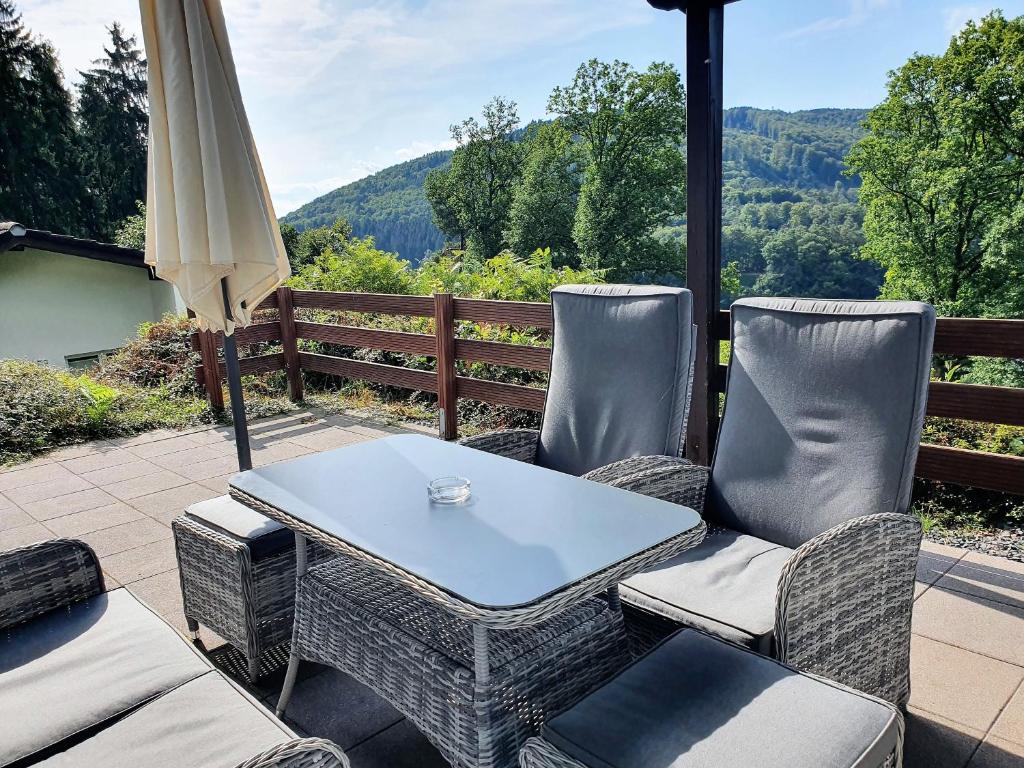 eine Terrasse mit einem Tisch, Stühlen und einem Sonnenschirm in der Unterkunft Ferienhaus Stausee Eifel in Biersdorf