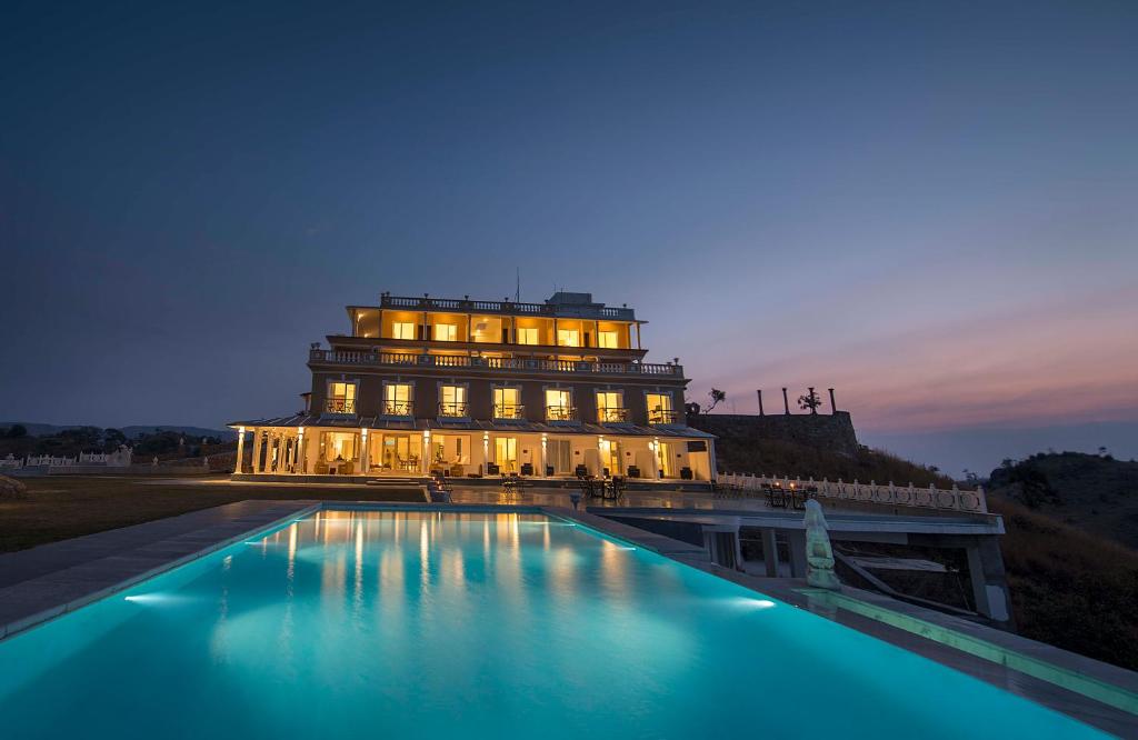 un edificio con una piscina delante de él por la noche en Fateh Safari Resort by Fateh Collection en Kumbhalgarh