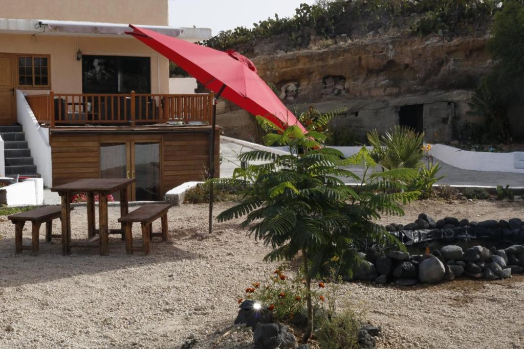 patio con tavolo e ombrellone rosso di Half wooden rural apartment a Fasnia