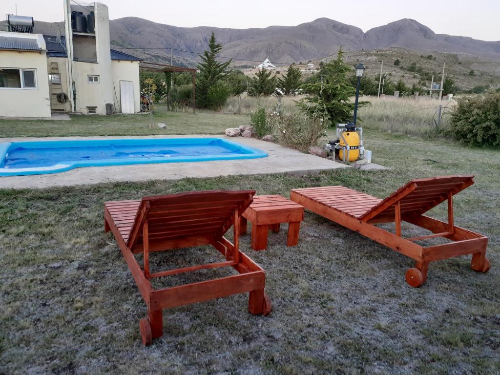 two benches and a picnic table in front of a pool at Lugar Maravilloso in Sierra de la Ventana