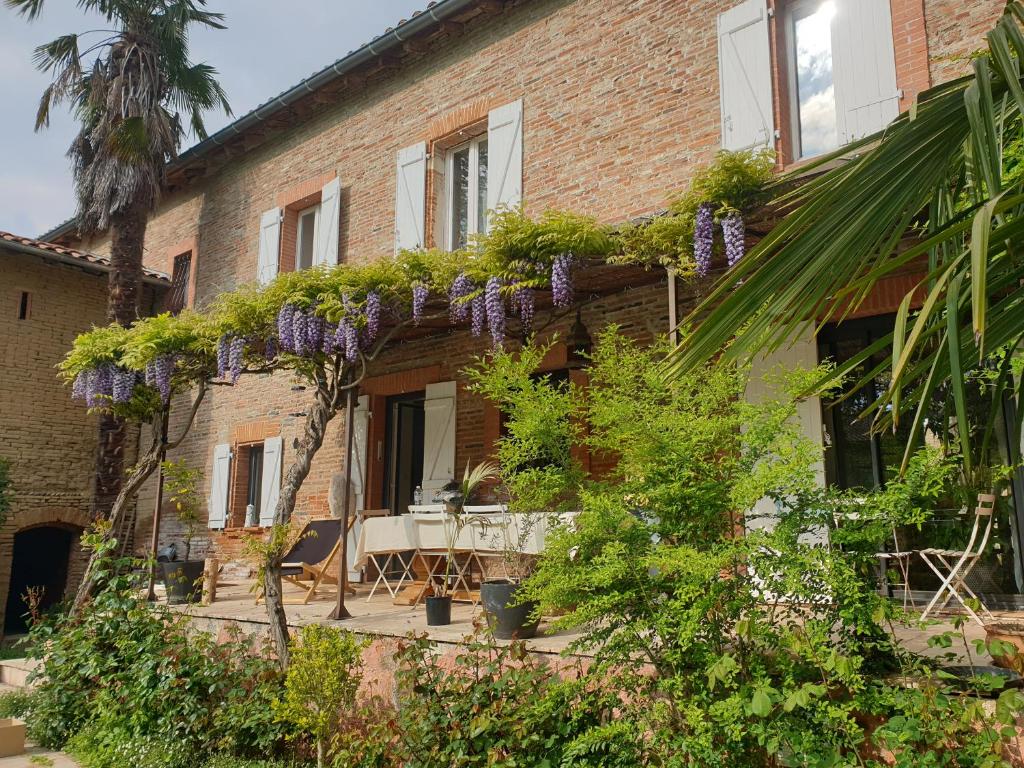 un edificio de ladrillo con una mesa y flores púrpuras. en Chambre de charme dans une propriété du 18ème, en Roquettes