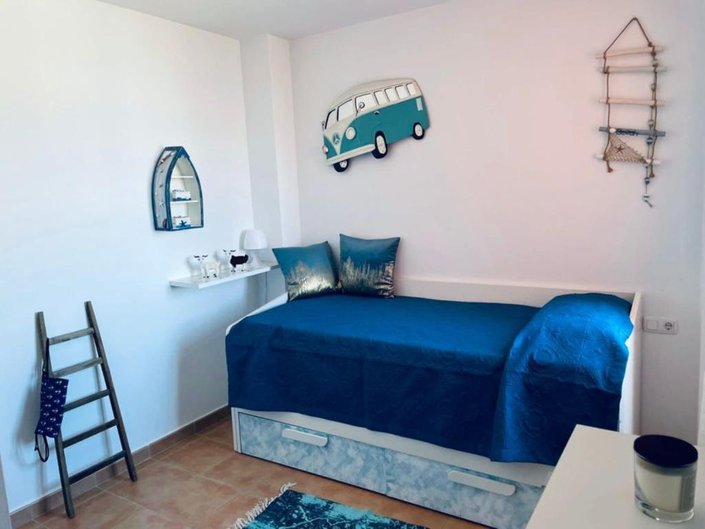 a bedroom with a blue bed with a van on the wall at Paradise Apartment in Corralejo