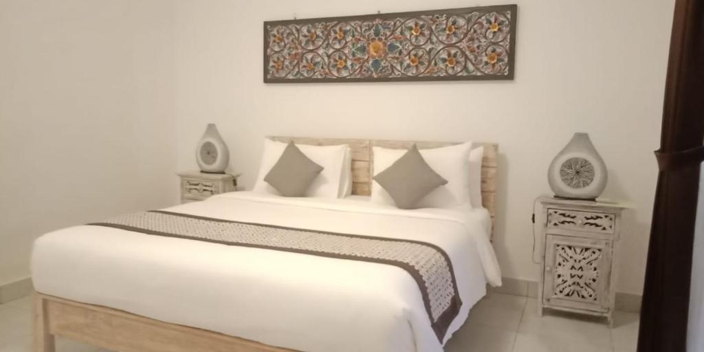 a bedroom with a white bed and two night stands at Kapri Balinese House in Ubud