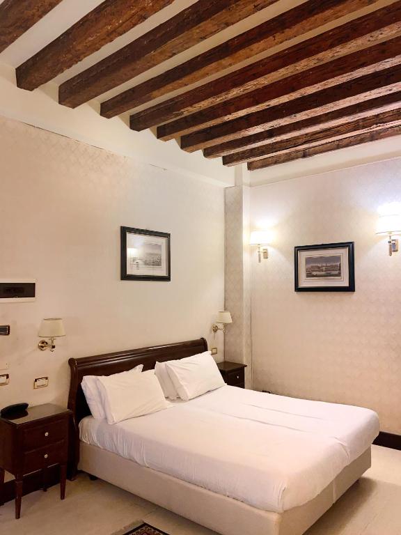 a bedroom with a white bed with a wooden ceiling at Ca' Del Nobile in Venice