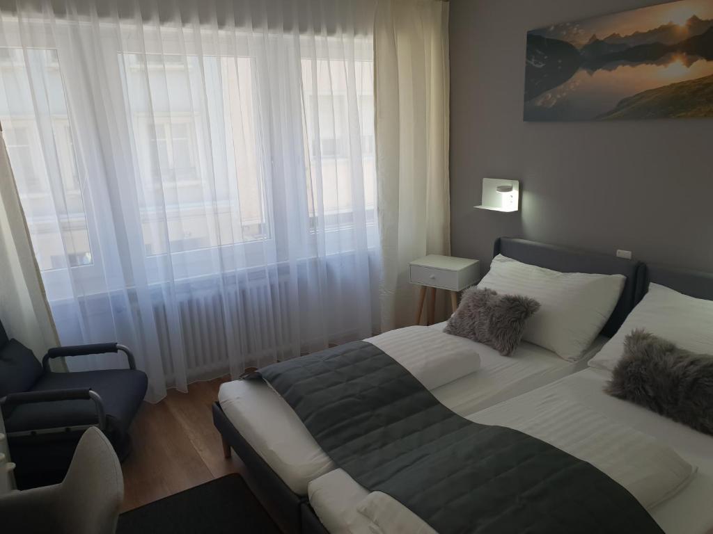 um quarto com uma cama e uma cadeira ao lado de uma janela em Hotel Elite em St. Gallen
