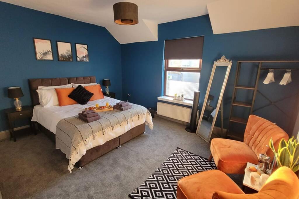 a bedroom with blue walls and a bed with orange pillows at Modern and Spacious 4 Bedroom House, Hot Tub, Wifi, Netflix, Parking in Paignton