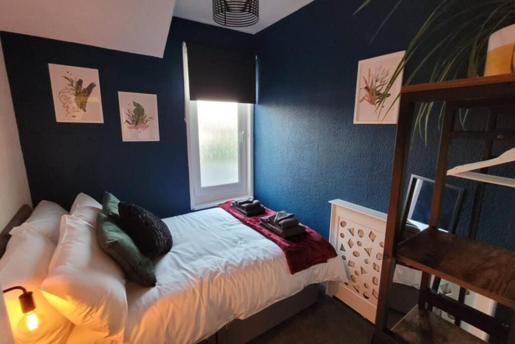 a bedroom with blue walls and a bed with pillows at Near beach, Modern and Spacious 4 Bedroom House, Hot Tub, Wifi, Netflix, Parking in Paignton