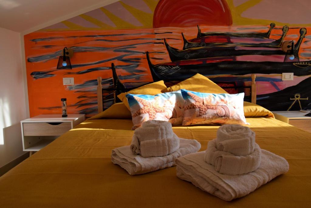 a bedroom with towels on a bed with a painting at Pozzo Antico Apartments in San Vito lo Capo
