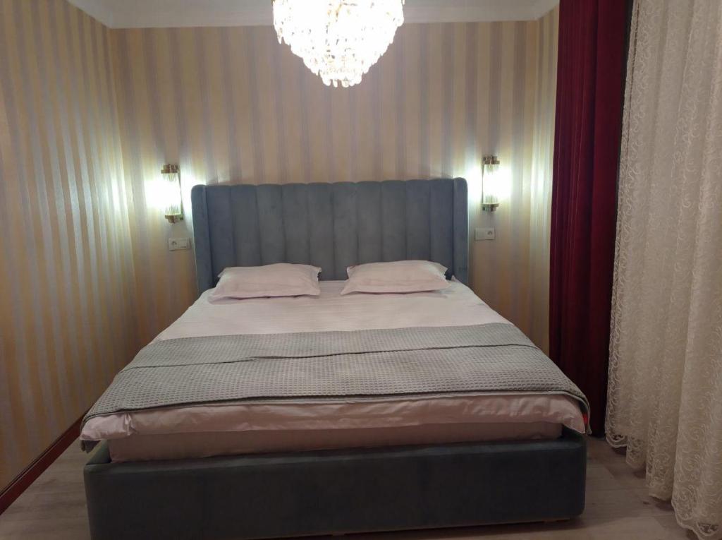 1 dormitorio con 1 cama grande y lámpara de araña en Comfortable Home Stay en Termiz