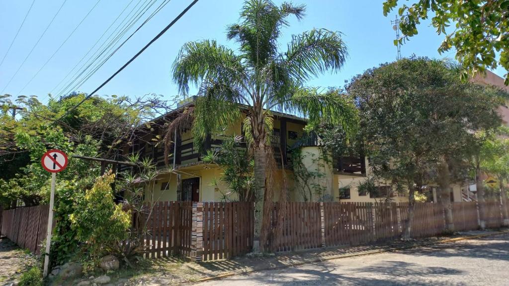 a house with a fence and a palm tree at Nossa Guarda Acomodações in Guarda do Embaú