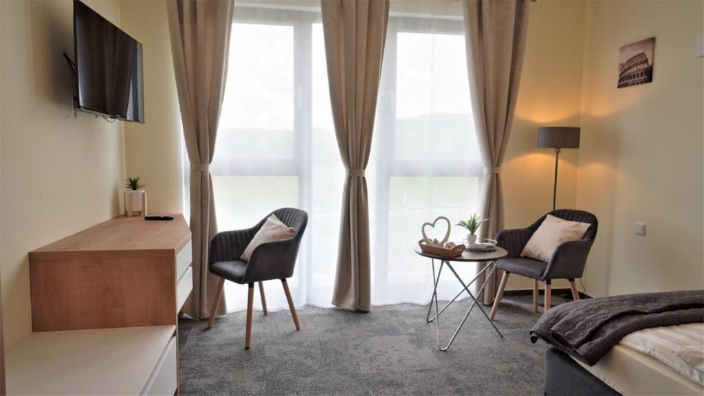 Un dormitorio con una cama y dos sillas y una mesa. en LikeDaheim Apartments, en Rosbach vor der Höhe