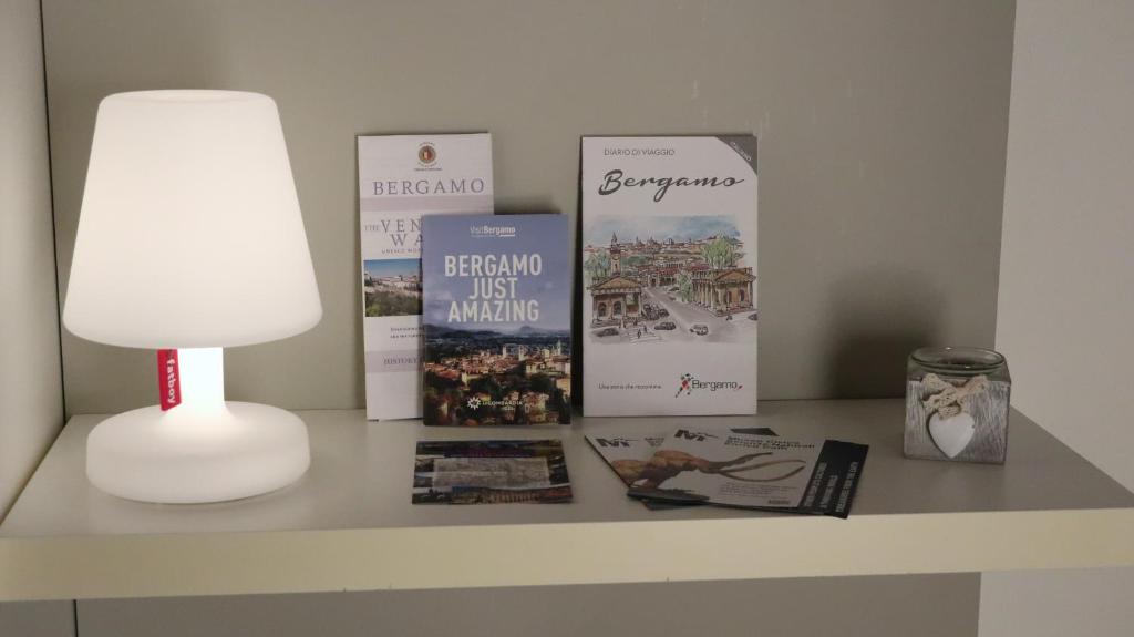 uma mesa com alguns livros e uma lâmpada sobre ele em Domus Solarii Holiday Home em Bérgamo