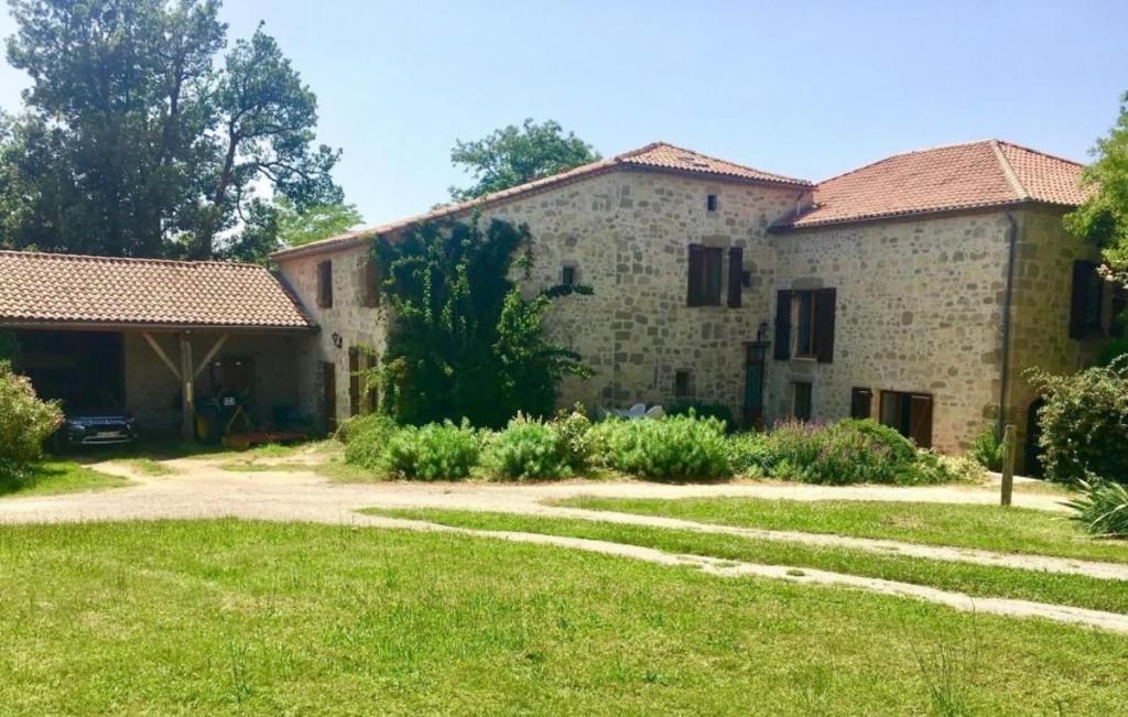 una antigua casa de piedra con un patio de césped en CHEZ SOPHIE -Chambres d’hôtes, Gîte et Gîte équestre, en Clermont-Dessous