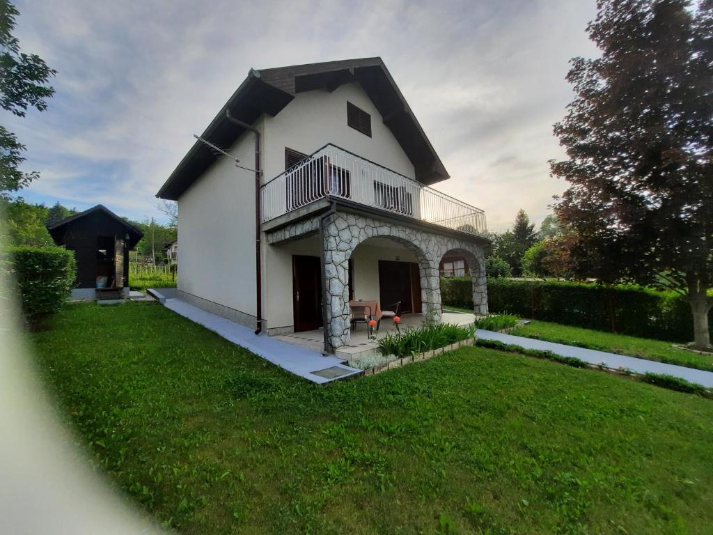ein weißes Haus mit einem Balkon und einem Hof in der Unterkunft Kuća za odmor VB-IDRO in Tuhelj