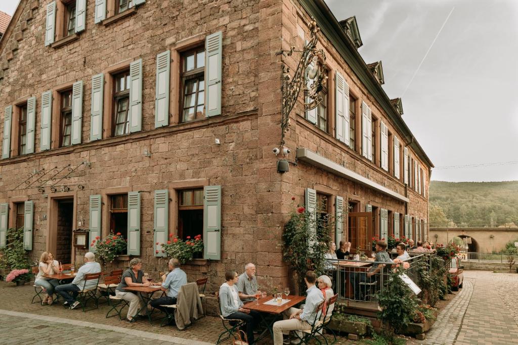 eine Gruppe von Personen, die außerhalb eines Gebäudes an Tischen sitzen in der Unterkunft Fränkischer Gasthof-Hotel zum Koppen in Gemünden