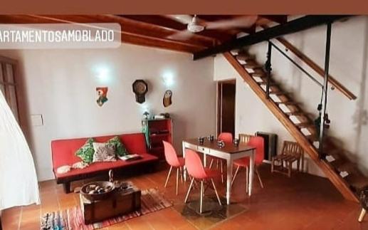 sala de estar con sofá rojo, mesa y sillas en La Querencia Apart RC en Río Cuarto