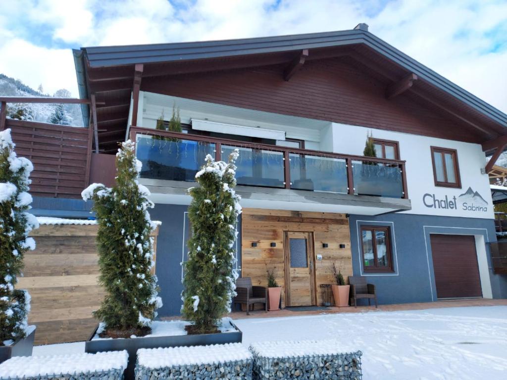 Chalet Sabrina mit Außenpool im Sommer في كابرون: منزل في الثلج مع شرفة