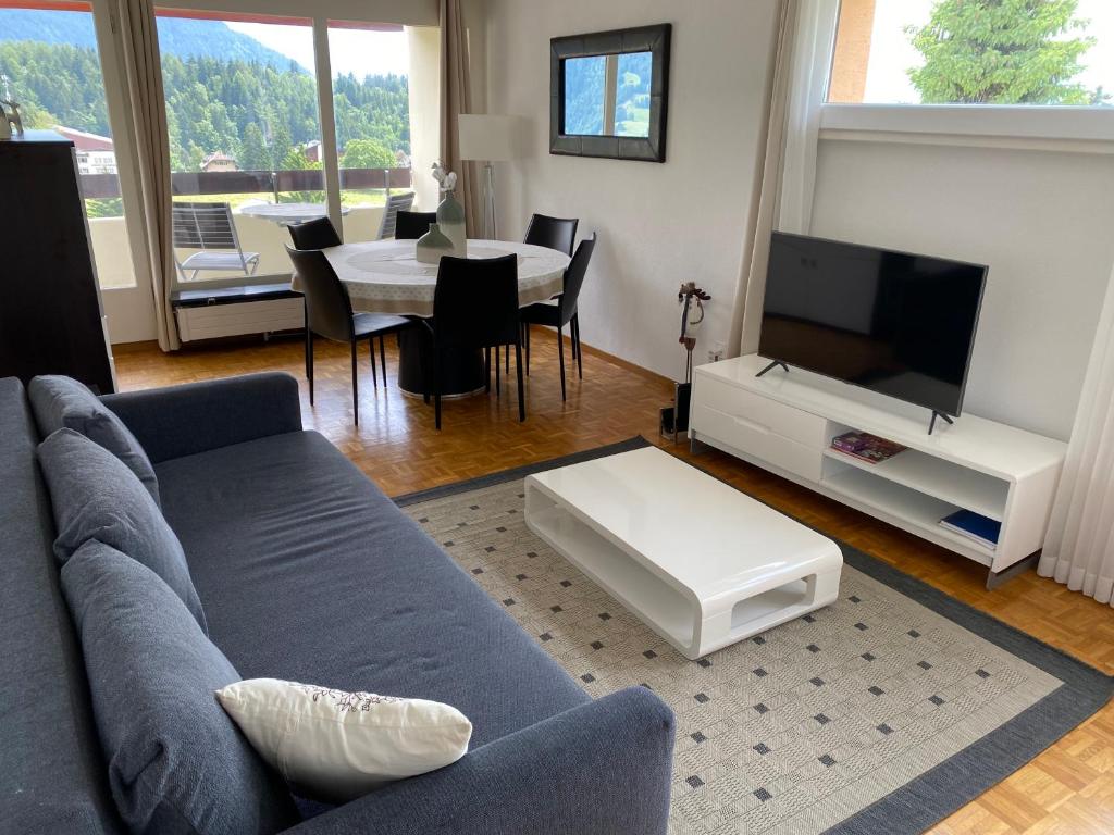 a living room with a couch and a tv and a table at Swiss Mountains in Leysin