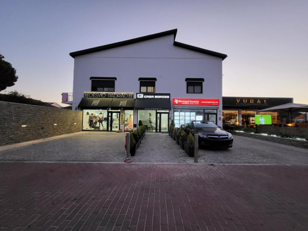 a white building with a car parked in front of it at Casa Borges in Charneca