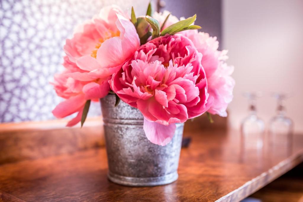 a metal vase filled with pink flowers on a table at Hôtel Royal Opéra in Paris